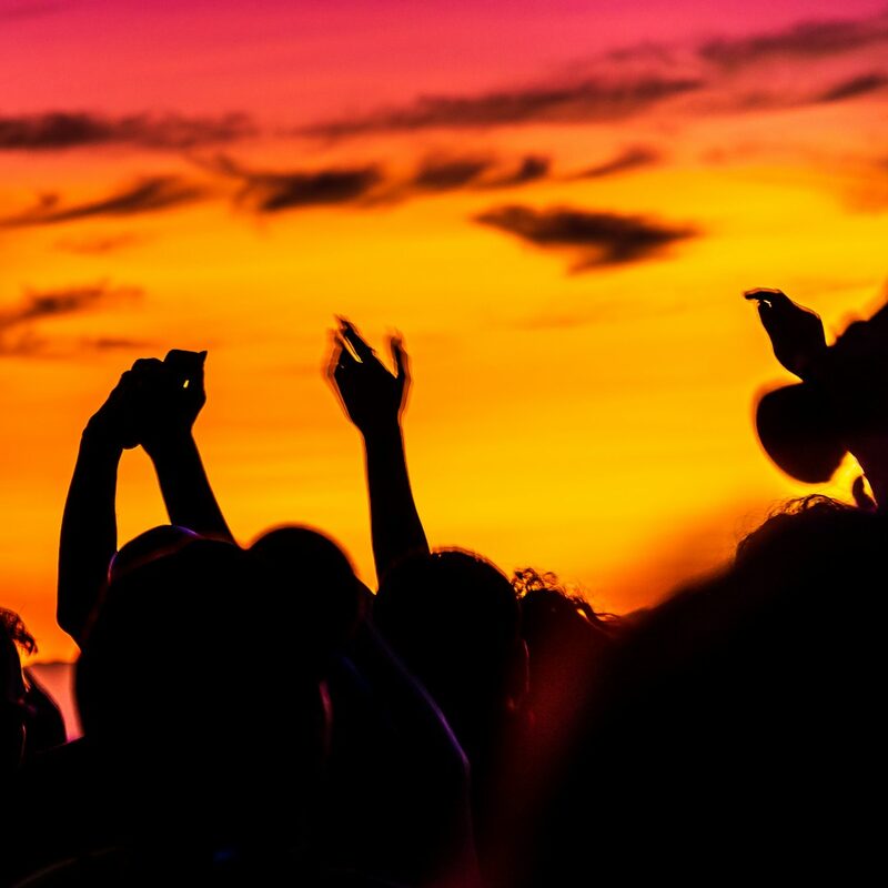 Crowd dancing at an outdoor party at sunset in Dubai